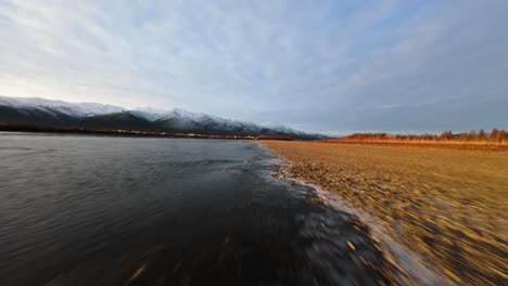 experience the stunning beauty of yakutia from above, where the vast river meets snow-capped mountains under the expansive sky. nature’s grandeur unfolds in each sweeping view.