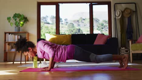 Mixed-race-woman-practicing-yoga-on-yoga-mat-at-home