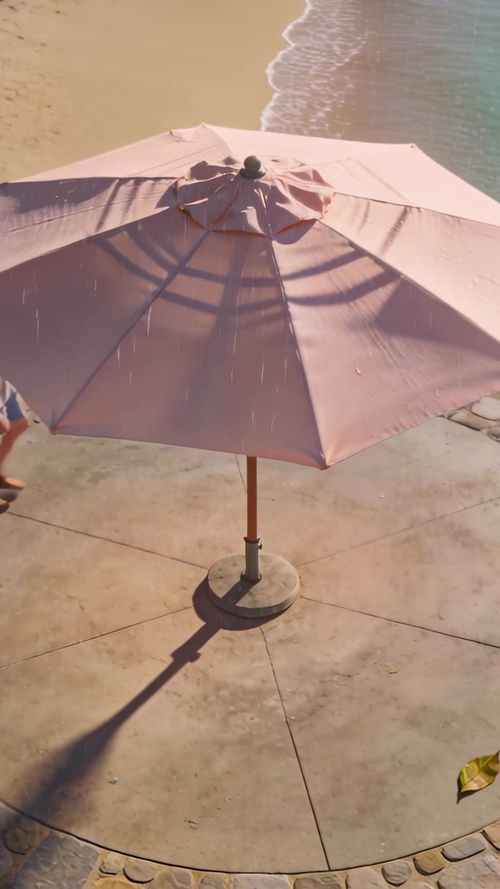 Video verticale: Entrando da sinistra, una coppia passa un ombrellone rosa da spiaggia su un patio proiettando ombre, con pantaloncini.