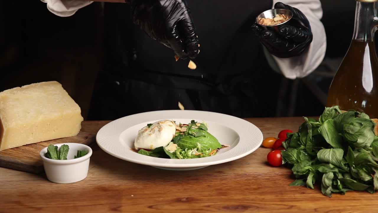 Chef Garnishing Fresh Burrata and Avocado Salad with Nuts