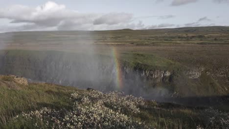 río cayendo entre acantilados con un arco iris brillante