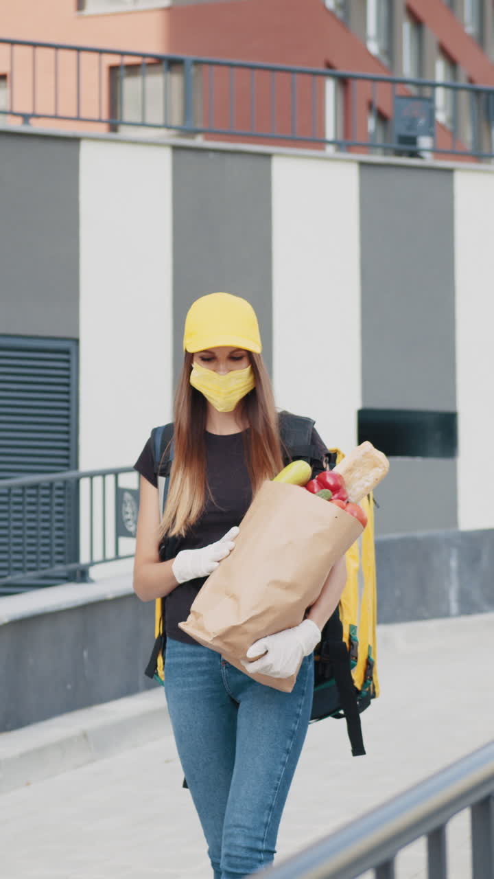 Delivery person wearing a mask and gloves carrying groceries outside