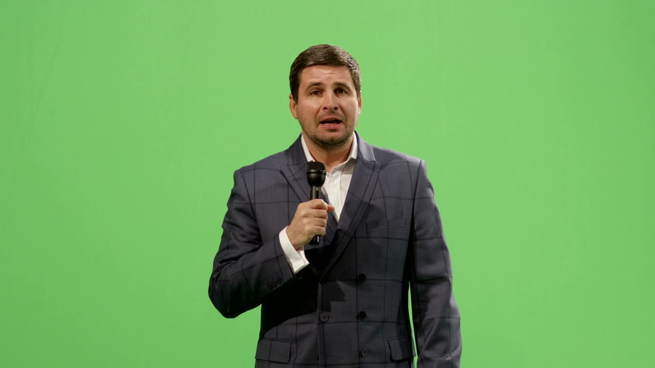 Media reporter with a microphone is talking on a mock-up green screen in the background.