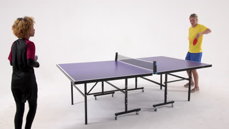 multiracial female table tennis players, serving and passing the ball on white background