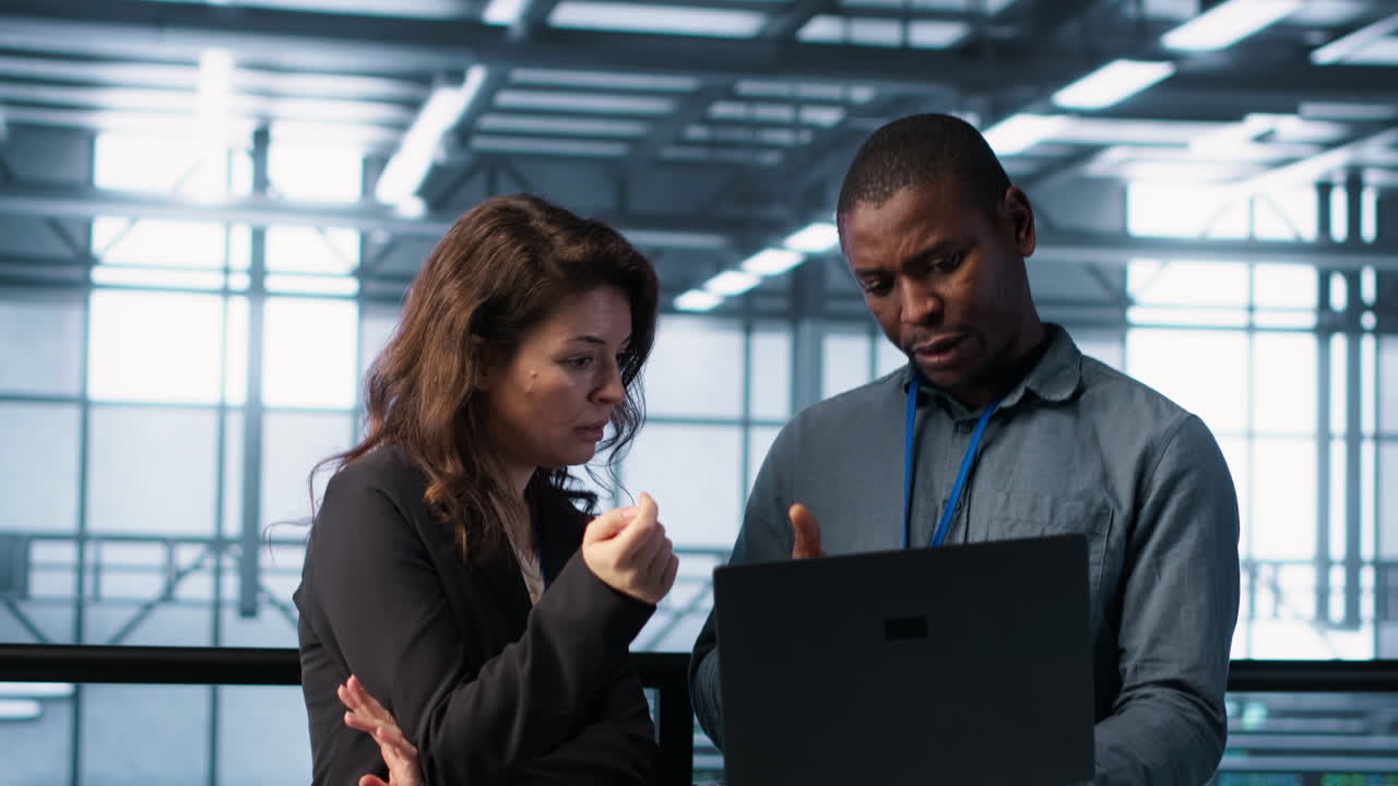 Engineers using laptop in data center, managing server virtualization