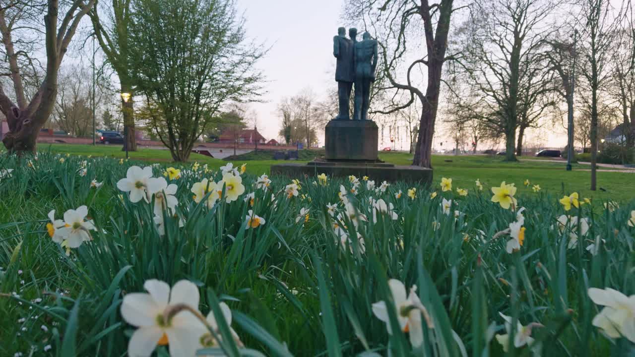 a calm and peaceful Dutch city town park in the Netherlands with sculpture and flowers plants and grass on the meadow from the ground low angle field of view in the evening sunset outdoors with trees
