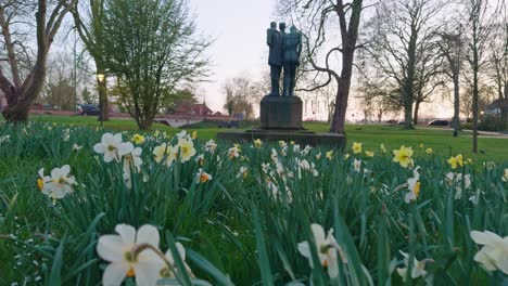 a calm and peaceful dutch city town park in the netherlands with sculpture and flowers plants and grass on the meadow from the ground low angle field of view in the evening sunset outdoors with trees