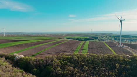 Eine-Windturbine-Auf-Einer-Riesigen-Grünen-Wiese-Mit-Klarem-Himmel-Und-Hügeln-In-Der-Ferne