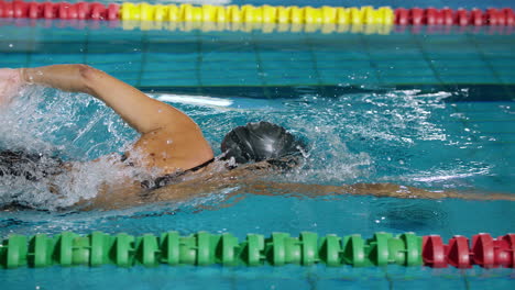 powerful female swimmer swimming breaststroke at speed, tracking shot