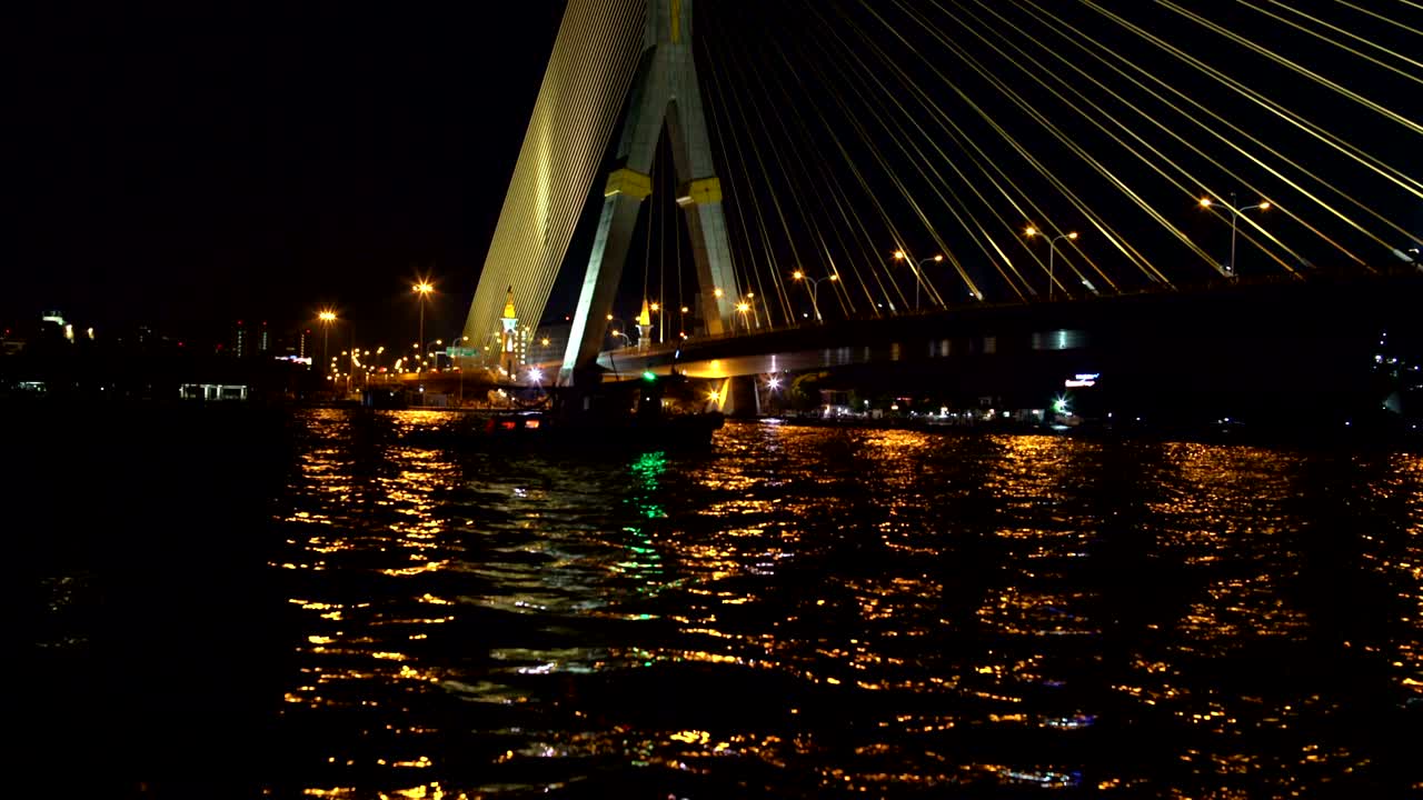 강을 가로지르는 케이블 다리. 강을 따라 보트가 항해한다.