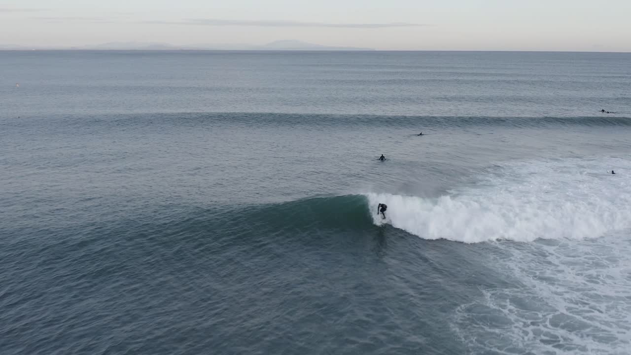 Surfista che cavalca la spalla dell'onda nelle fredde acque dell'Oceano Atlantico, vista aerea