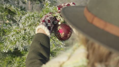 bola de copo de nieve de decoración navideña roja colgante en la rama de un árbol en el frío y soleado día de invierno