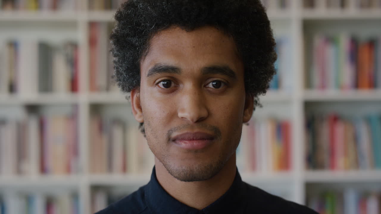 retrato confiado joven hombre de raza mixta buscando empresario masculino exitoso en el fondo de la estantería de la biblioteca