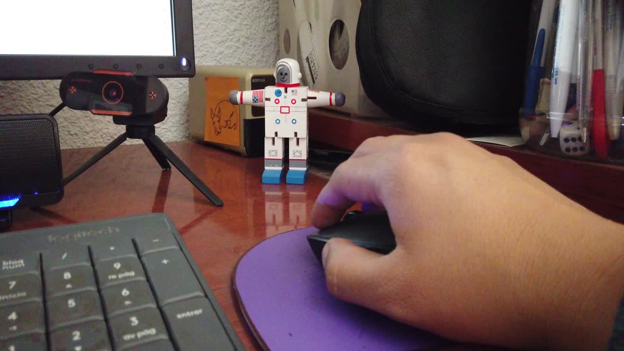 Fixed close-up shot of a man's hand using a computer mouse while working at a wooden desk in an office