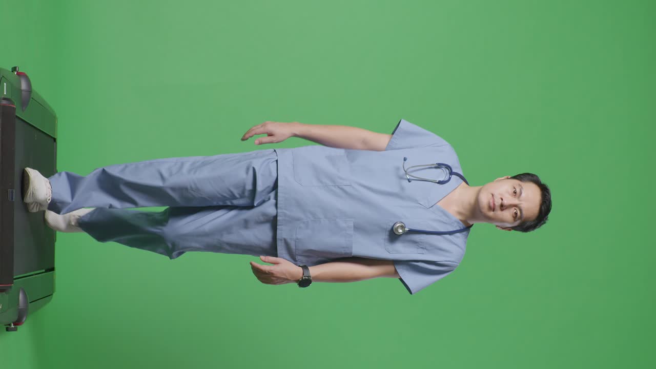 병원에서 녹색 스크린 배경에서 걸어가는 스테토스코프를 가진 아시아 남성 의사의 몸이 가득 차 있습니다.