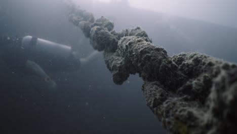 close-up of a heavy underwater chain with diver equipment in murky water
