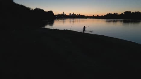 a fisherman with a net wades through the water and repeatedly puts the net in the water