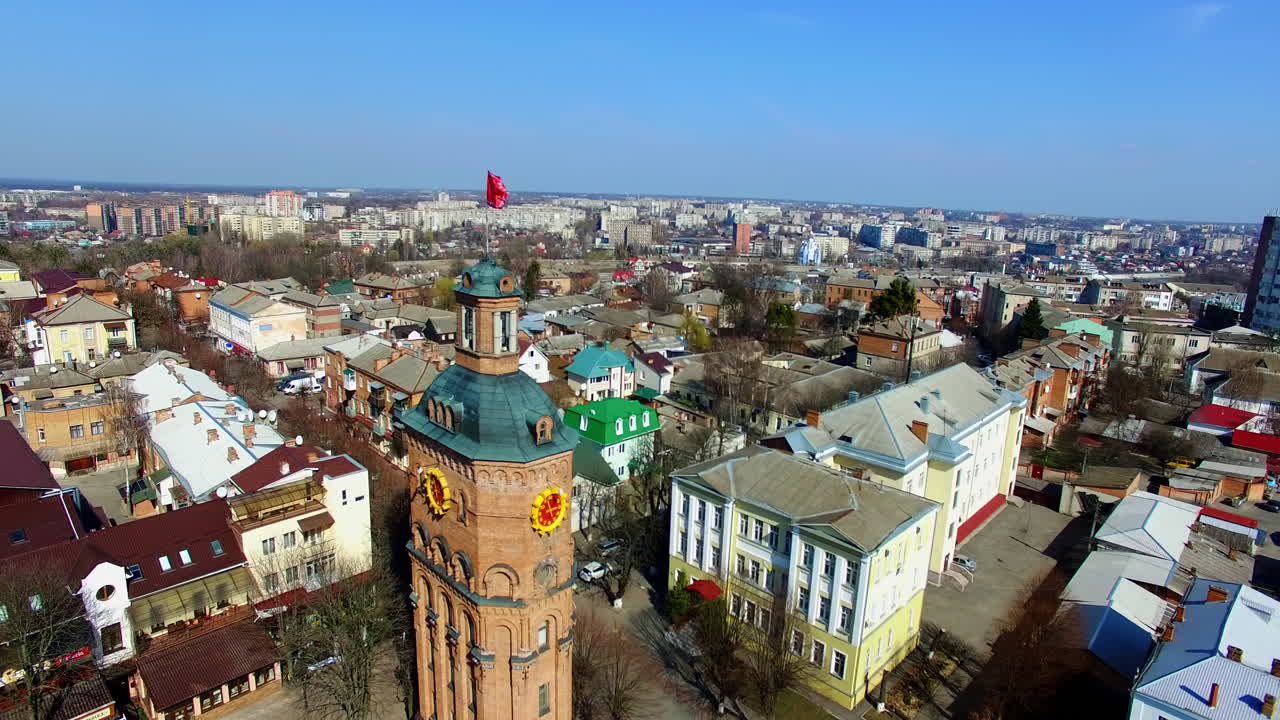 Sunny view of the Ukrainian city at daytime. Drone footage flying around the brick wall tower with a flag on top. Aerial view.