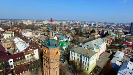 sunny view of the ukrainian city at daytime. drone footage flying around the brick wall tower with a flag on top. aerial view.