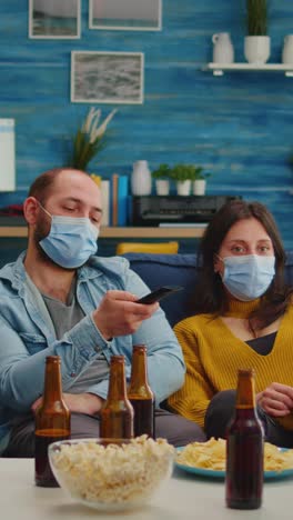 vertical video: diverse people relaxing together watching tv holding remote control
