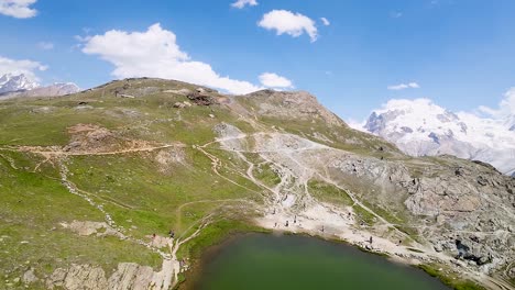 High-altitude-flight-towards-the-beautiful-Swiss-Alps-over-a-small-glacial-lake-in-Zermatt,-Switzerland,-Europe