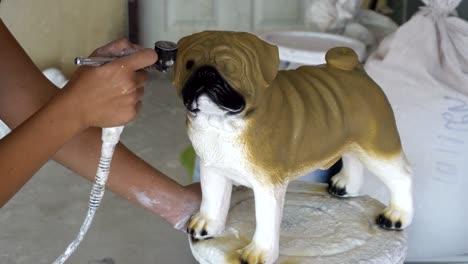 woman hand in glove paint pug dog statue details by airbrush