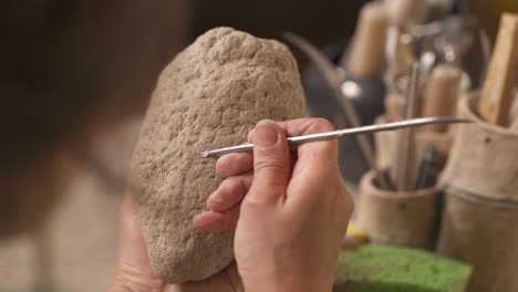 A front view of an inspired potter carefully glazing ceramics sculpture using professional tools. Artist working in workshop. Modern art concept