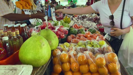 cliente pagando frutas en el mercado de sir selwyn clarks en victoria town en mahe, seychelles, pagando las naranjas con la moneda local