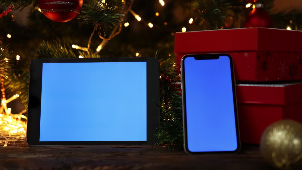Christmas background red gift box tablet smartphone blue screen fir tree lights