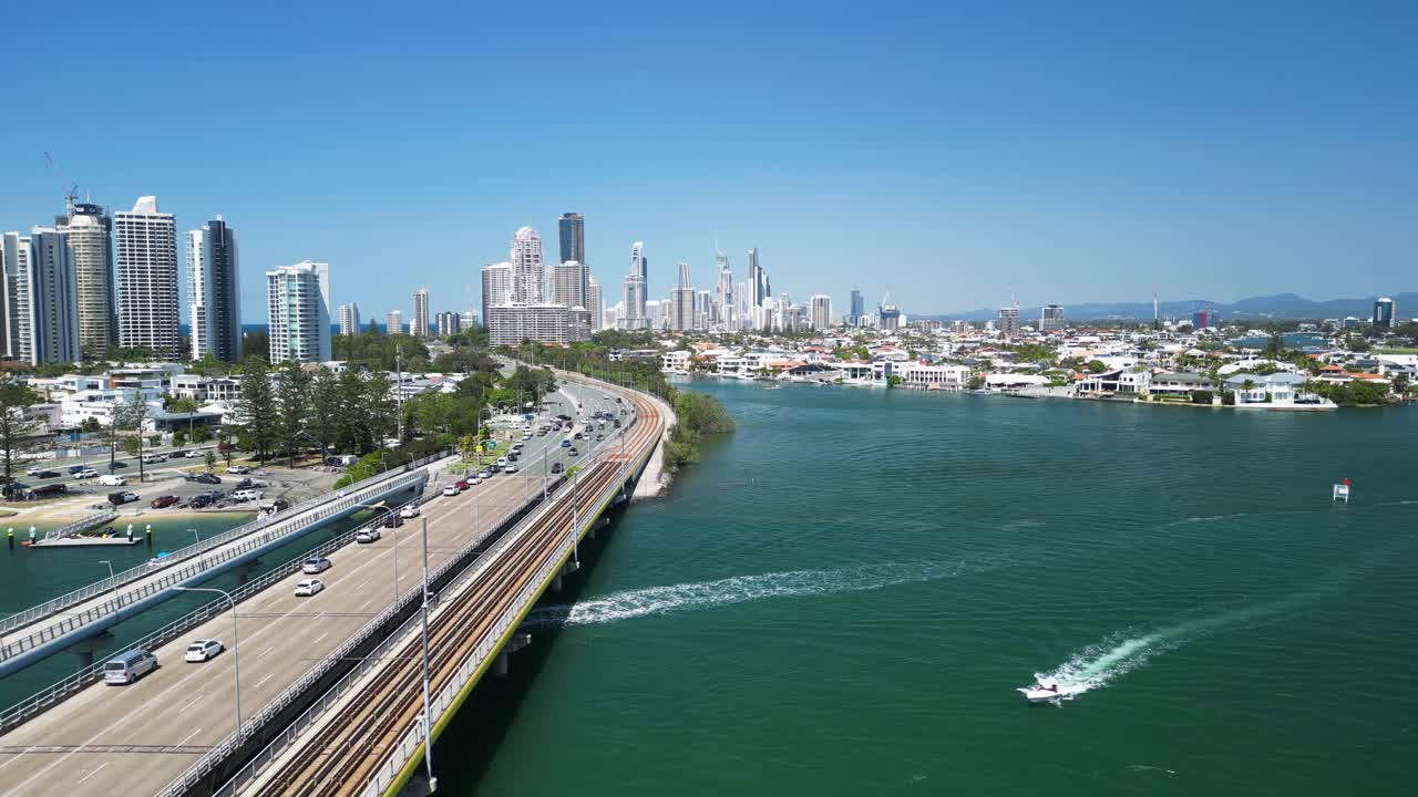 Commuter traffic enters a towering urban city skyline across a bridge over a coastal body of water. Gold Coast Australia