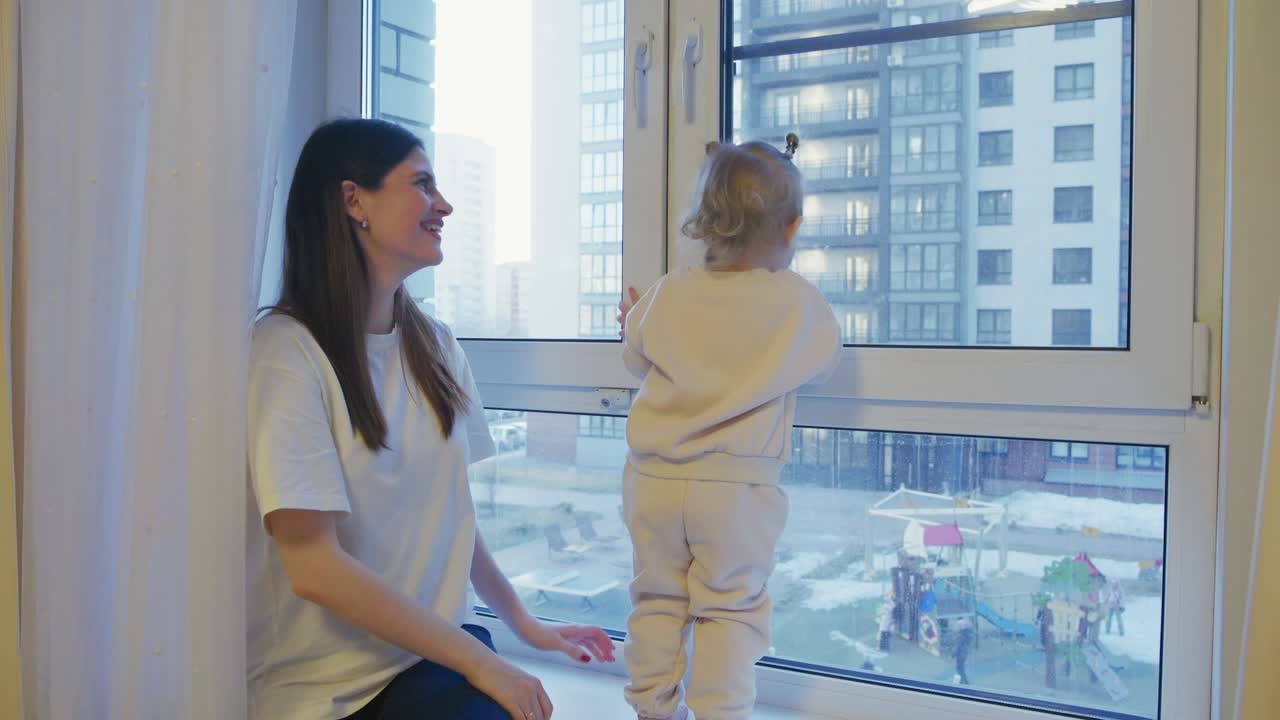 Mother and Baby Looking Out Window at City View