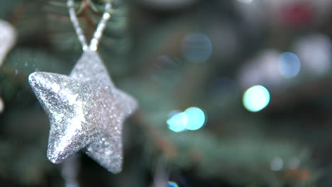 shiny reflective star-shaped toy hanging on christmas tree, close-up static