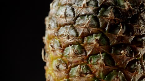 detailed macro shot of rotating pineapple fruit isolated on black background