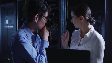 diverse female and male it technicians using laptop checking computer server