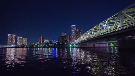 Luz-Nocturna-Tokio,-Tsukuda,-Rascacielos-Toyosu-Y-Puente-Sobre-El-Río-Sumida-Yakatabune,-Embarcación-De-Recreo