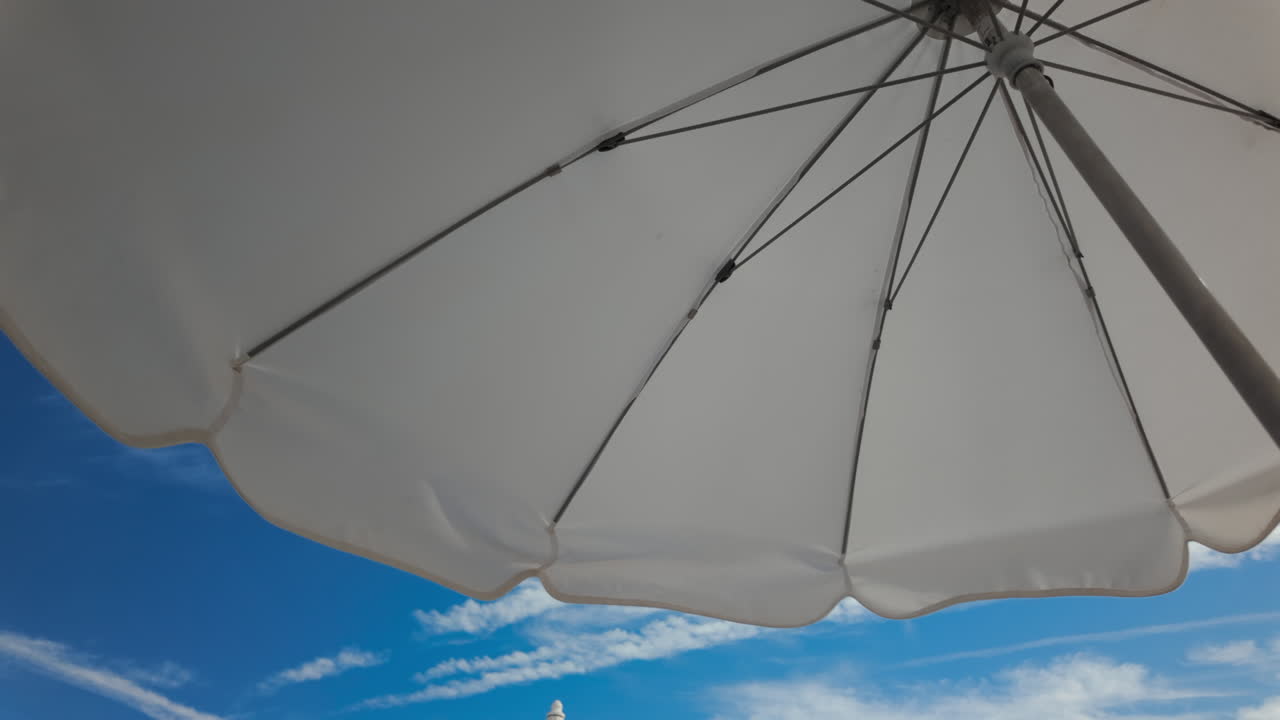 Sunny seaside view with white beach umbrellas framing a bright blue sky and calm sea