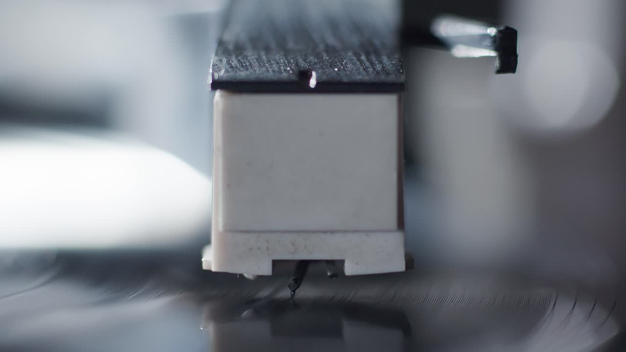 Breathtaking close-up of the needle of a record player being manually placed on the record while a vinyl record is playing