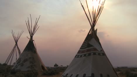 indian teepees stand in a native american encampment at sunset