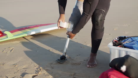 primer plano de un surfista masculino irreconocible con una pierna artificial en la costa