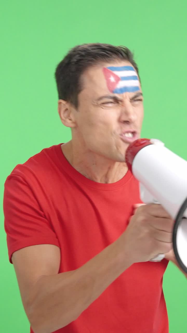 Excited man with cuban flag on face using a megaphone