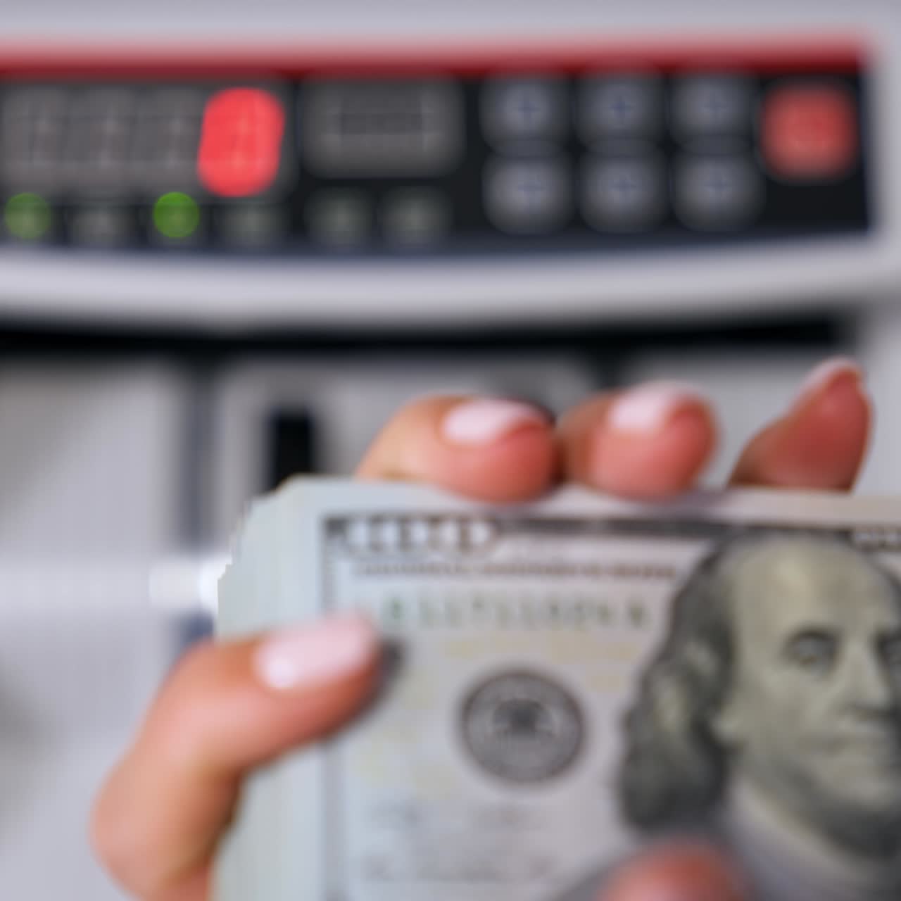 Dollari USA nelle mani di una donna. Una mazzetta di banconote da cento dollari nelle mani su sfondo sfocato di una macchina contabanconote automatica. Concetto di finanza. Primo piano.