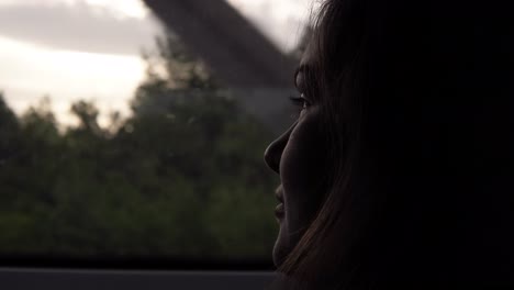 Close-up-of-woman's-face-looking-to-window-in-moving-train.-Darkened.-Evening-dusk.-Side-view