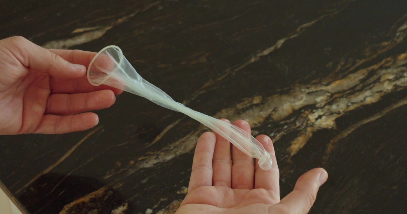 Person stretching a condom with both hands to test flexibility, durability and protection quality.