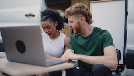 couple working on laptop outside of campervan