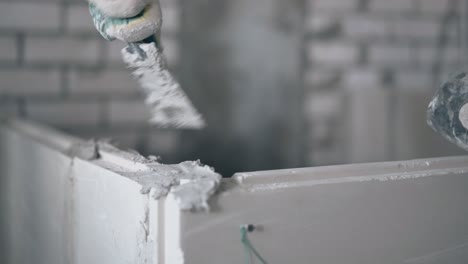 painter hand holds putty knife and puts substance on wall