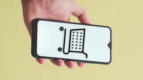 hand holding a phone in which the online shopping cart animation appears on the screen