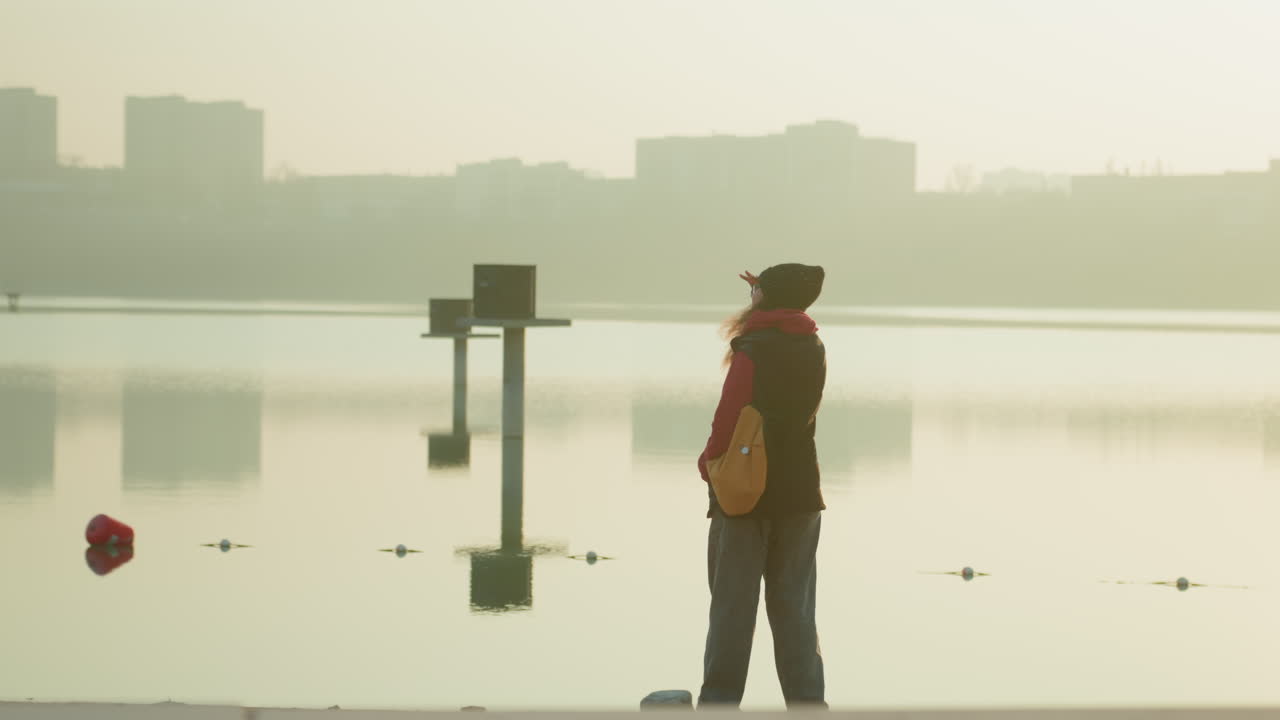 寧靜黎明景色。寧靜河流與日出城市。平靜水面倒影映照黎明時分的城市剪影。寧靜晨景捕捉城市倒影映照在平靜流動的水面上