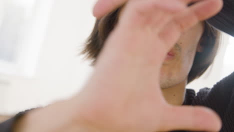 close up view of contemporary male japanese dancer who is training dance moves with her hands and face while looking at camera in the studio 1