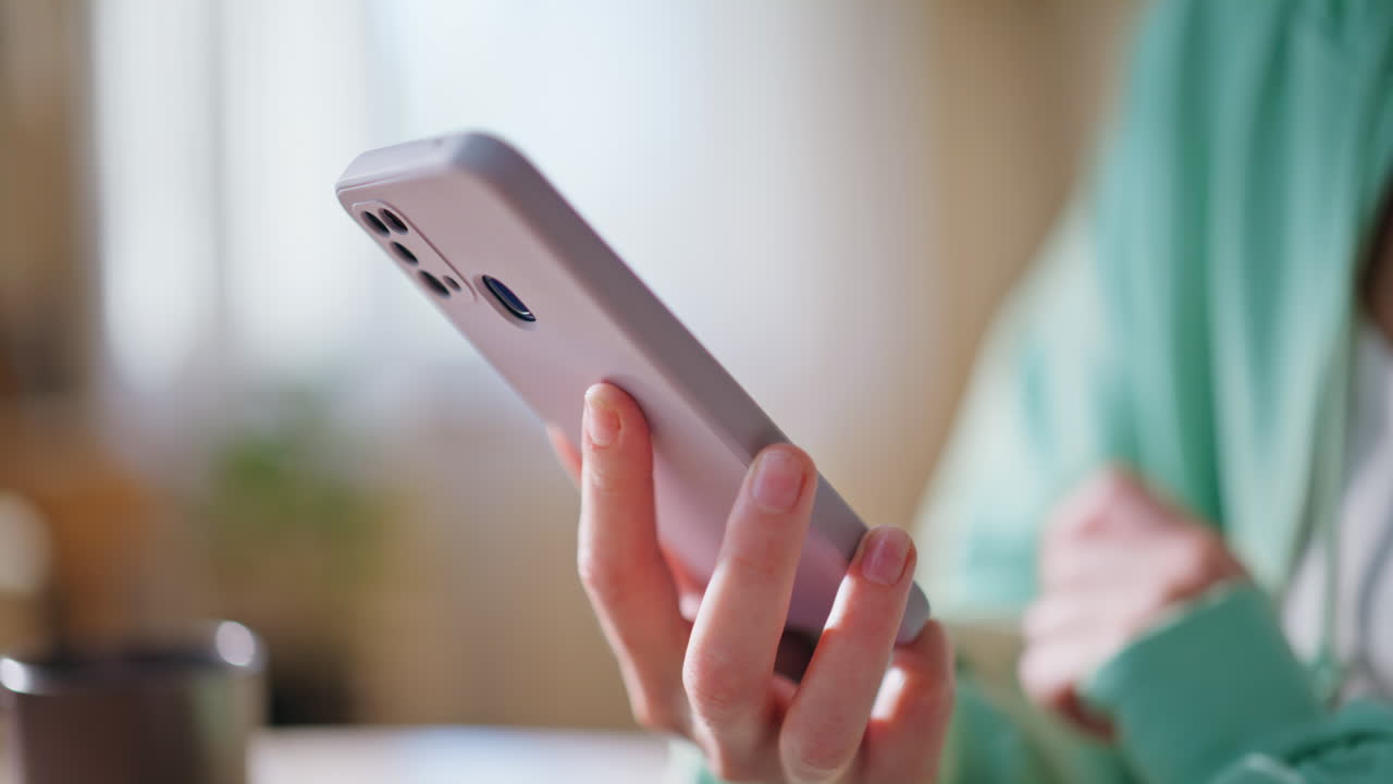 Woman hands holding mobile phone in modern light apartment closeup. Unknown girl