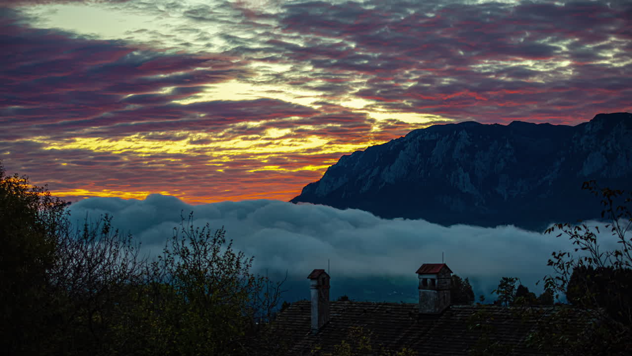 el lapso de tiempo de las nubes flotando sobre la ciudad montañosa de los alpes austriacos bajo el dramático cielo de la puesta de sol, nubes de niebla bajo el cielo de la caída del sol